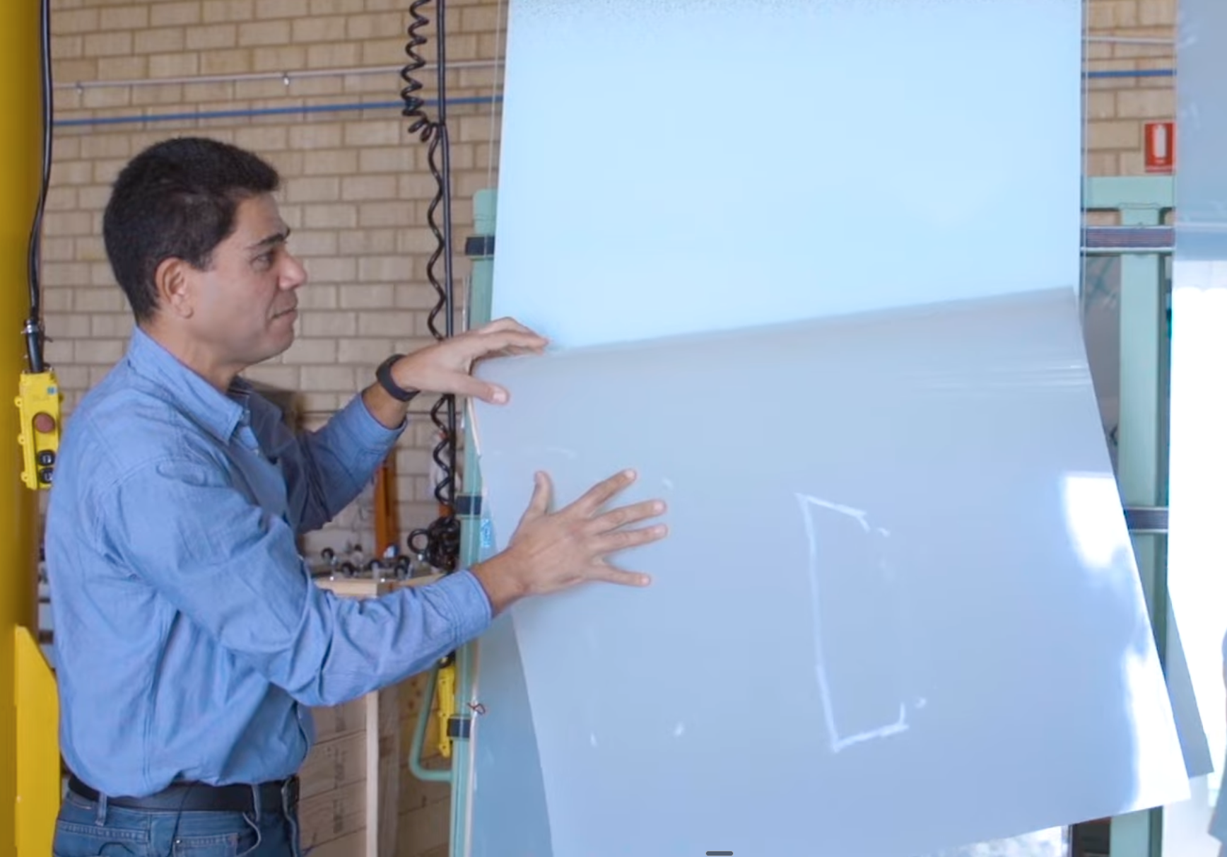 A professional installer carefully removes a large sheet of opaque smart tint from an interior glass wall, highlighting the process of replacing or removing lower-quality adhesive smart films that have failed or reached the end of their short lifespan.